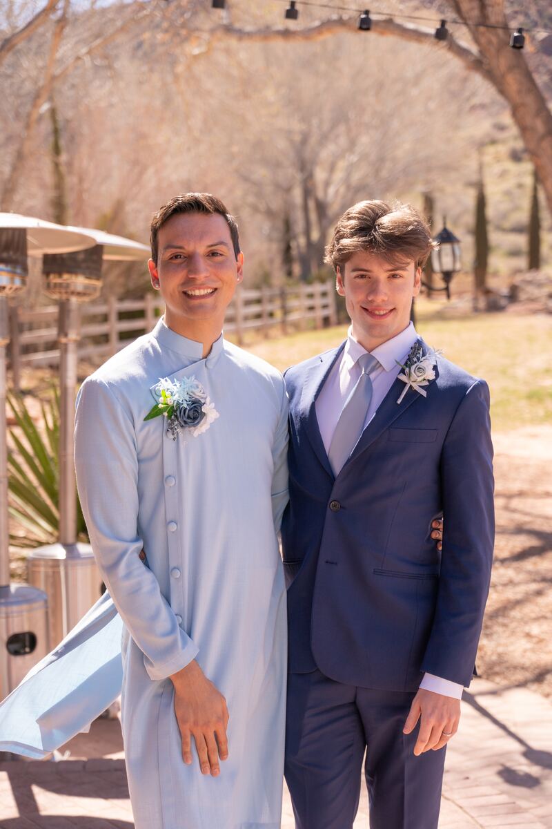 Two grooms with boutonnieres smiling outdoors