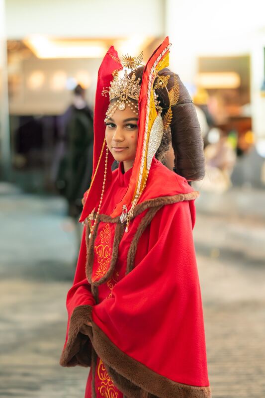 Cosplayer in a red embroidered robe and headdress, sharp gaze