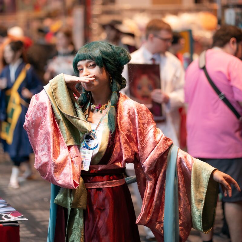 Cosplayer in flowing silk sleeves, mid-gesture, on the con floor