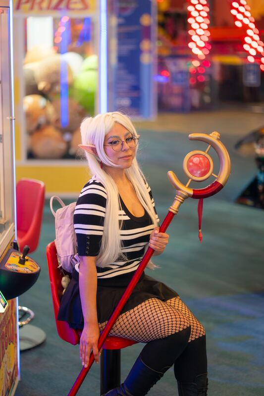 Cosplayer with a staff, seated against neon lights