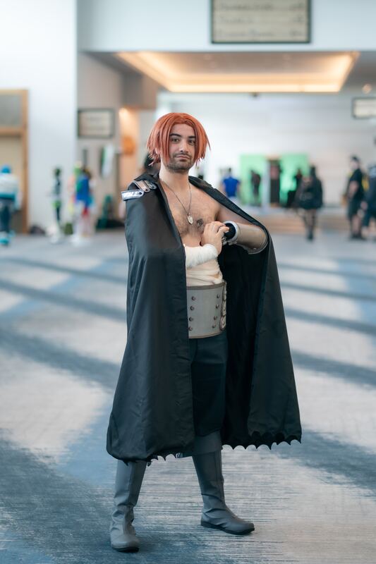 Cosplayer in a dark cape and armor, convention hall