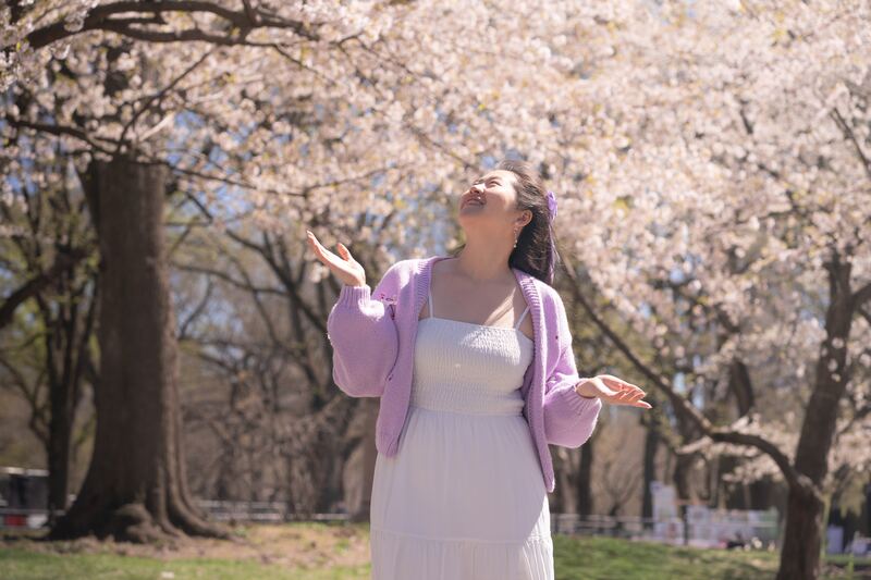 Woman with eyes closed under cherry blossoms
